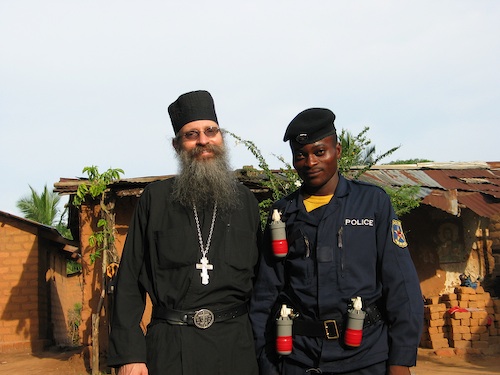 Father Peter, former policeman, with the parishioner Demetrios, active duty
    policeman. Demetrios' salary is $30 a month plus room and board. Demetrios is wearing three
    tear gas grenades.