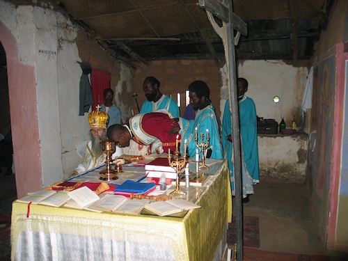 Subdeacon Chrysostom kissing the four corners of the altar.