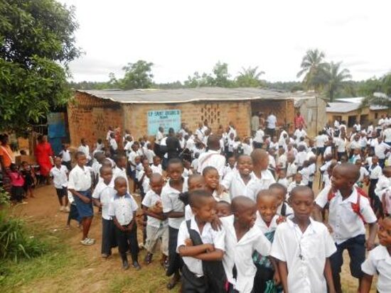Pupils in white and blue uniforms lined up in front of the school buildings