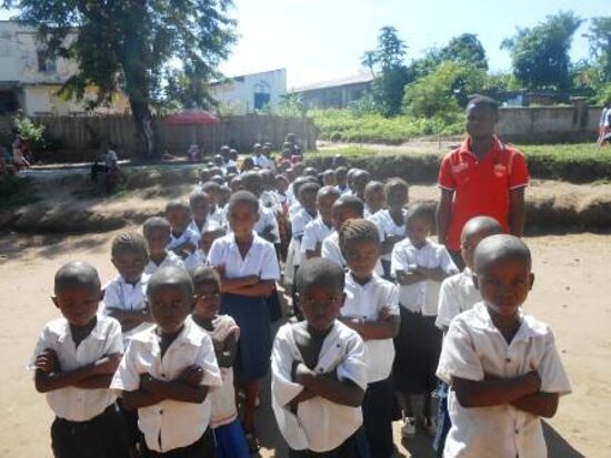 Pupils lined up in the schoolyard with a teacher