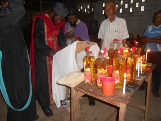 Priests at a table with bottles of oil and candles for the Holy Unction