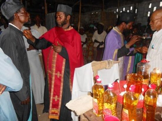 Priests in vestments anointing the faithful at the Holy Unction, bottles of oil on the table