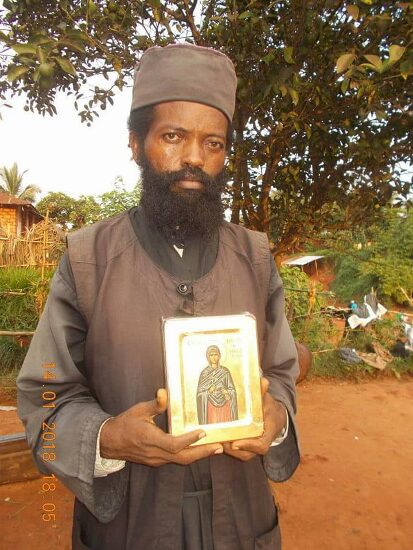 Father Theophile holding an icon, outdoors