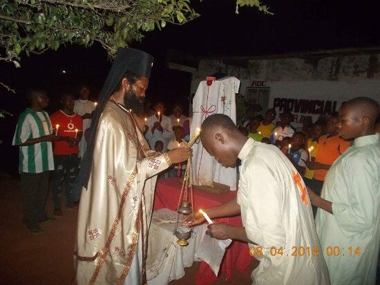 Father Theophile censing by night, a young man in a white robe beside him