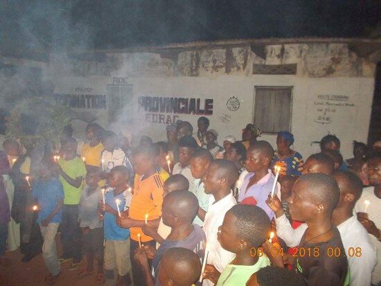 The faithful with candles in the incense smoke of the procession