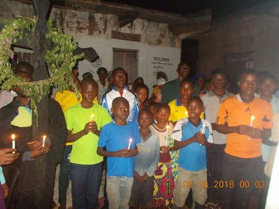 The faithful with candles around the cross hung with green branches