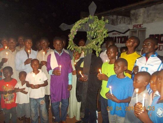 The faithful with candles around the cross hung with green branches
