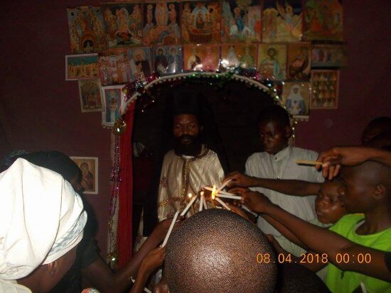 Father Theophile giving the Paschal light to the faithful, who light their candles from his