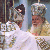Patriarch Teoctist of Romania gives a fraternal kiss to Pope John
  Paul II at their concelebration of the Divine Liturgy in Bucharest in May of 1999.